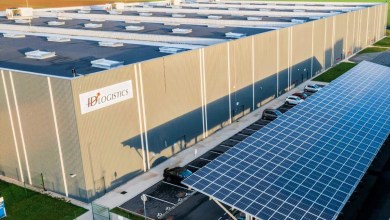 A large warehouse with solar panels on one side and ID Logistics sign.