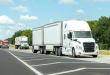 a white tractor pulling pup trailers