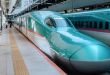 A front view of an aqua-colored Shinkansen bullet train in Japan.