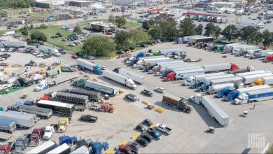 Aerial view of a busy truck stop parking lot filled with semi-trucks and trailers.