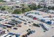 Aerial view of a busy truck stop parking lot filled with semi-trucks and trailers.