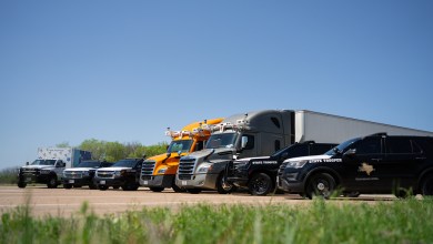 Bot Auto autonomous trucks lined up with Texas Highway Patrol SUVs and a first-responder ambulance