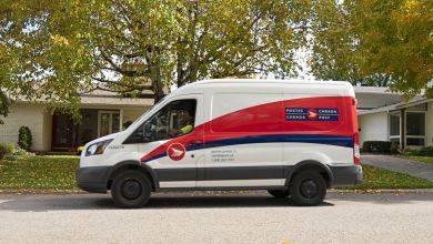 A red-white-and-blue Canada Post delivery van on a tree-lined neighborhood street.