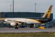 A brown-tailed UPS cargo jet is parked in front of a UPS terminal, as seen from the side rear.
