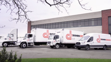 Dohrn fleet lineup with white tractor, box trucks, and cargo van parked outside a terminal building