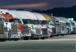 Fleet of semi-trucks lined up at dusk, illustrating carriers and small fleets using freight AI agents and TMS technology