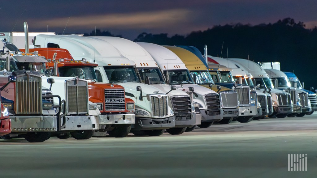 Fleet of semi-trucks lined up at dusk, illustrating carriers and small fleets using freight AI agents and TMS technology