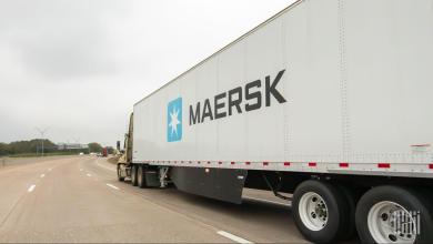Maersk semi-truck hauling a white trailer with the company logo on a multi-lane highway.