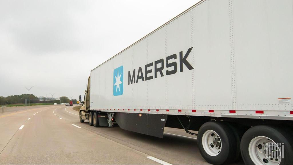 Maersk semi-truck hauling a white trailer with the company logo on a multi-lane highway.