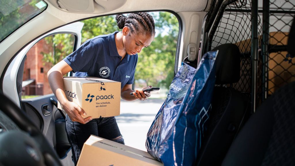 View from inside vehicle of a Paack delivery driver grabbing a parcel from the passenger seat.