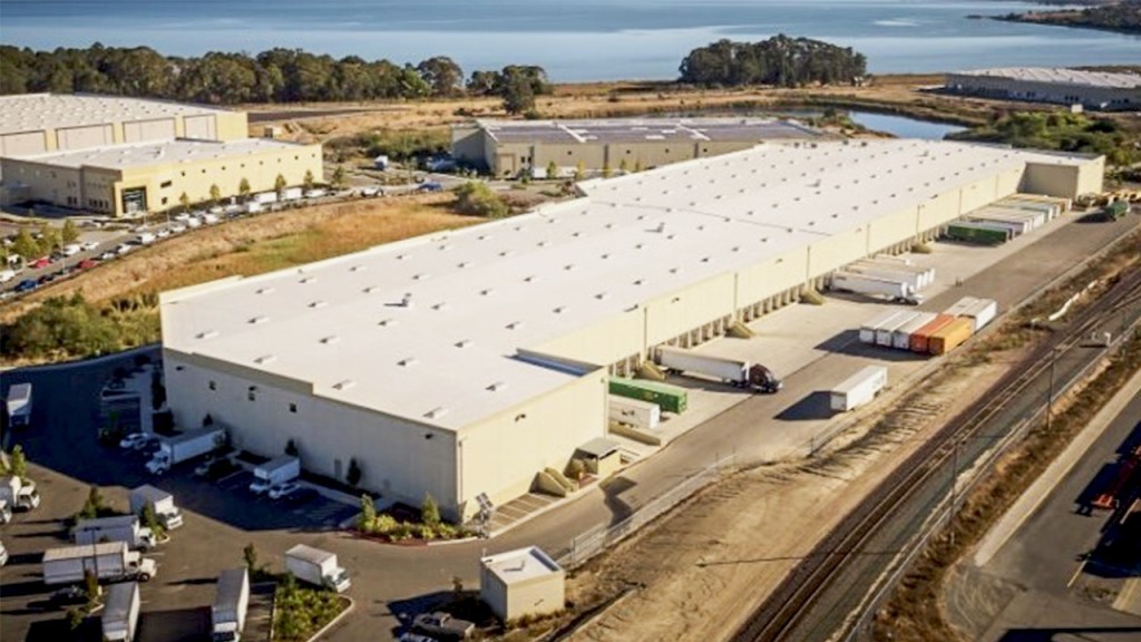 An aerial view of a large warehouse with trucks parked at the docks.