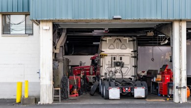 Technicians service a heavy-duty truck in a shop bay, where fleet repair costs concentrate.