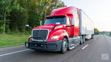 a red sleeper cab pulling a white trailer on a highway