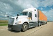 a white Schneider sleeper cab pulling an orange Schneider trailer on a highway