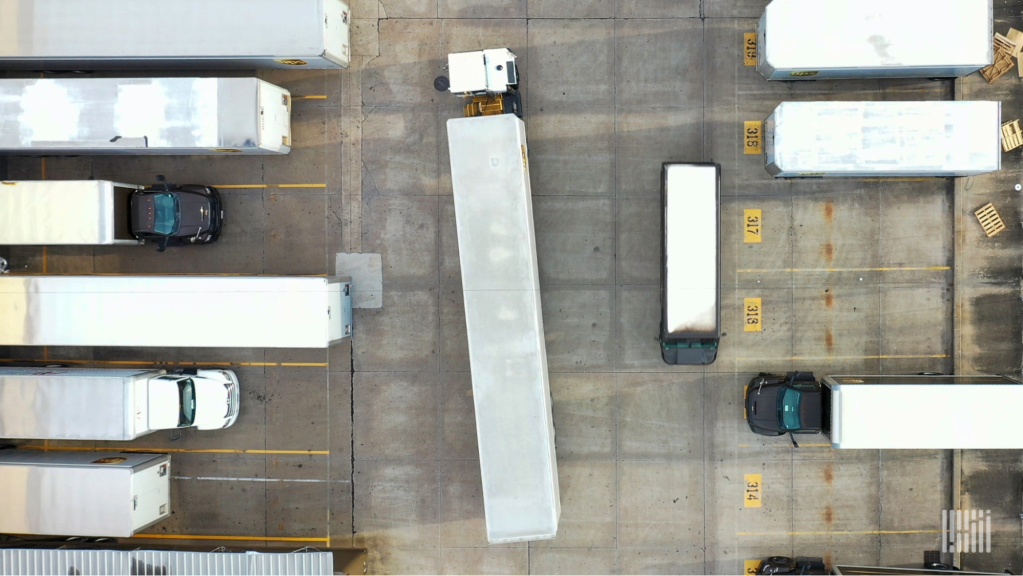A busy truck yard with terminal tractors and trailers in parking spots Primary focus keyword: yard automation