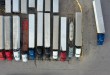 Tractor-trailers parked in rows at a freight terminal, seen from above, as Alvys acquires Optym’s LoadOps customers