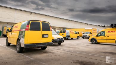 Yellow DHL Express vans are spread out in a company parking lot.