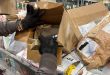 An inspector rips open a package on a U.S. Postal Service conveyor belt full of packages.