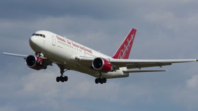 An Omni Air passenger jet approaches an airport with wheels down.