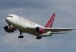 An Omni Air passenger jet approaches an airport with wheels down.