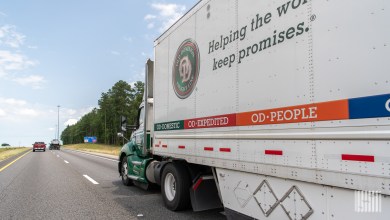 a side view of an Old Dominion trailer being pulled by an OD tractor on a highway