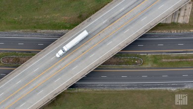 Aerial view of a white tractor-trailer crossing a highway overpass above a divided interstate