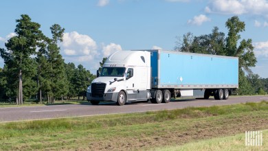 a white sleeper cab pulling a blue trailer