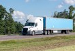 a white sleeper cab pulling a blue trailer