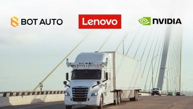 Autonomous truck with roof sensors crosses a bridge under Bot Auto, Nvidia and Lenovo logos for their AD1 computer deal