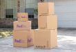 FedEx and UPS packages stacked up in a residential driveway after delivery.