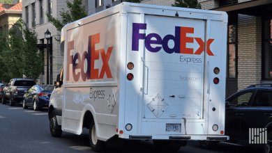 A rear angle view of a FedEx delivery van parked on a city street.