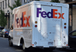 A rear angle view of a FedEx delivery van parked on a city street.