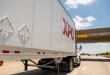 An XPO trailer being pulled on a highway