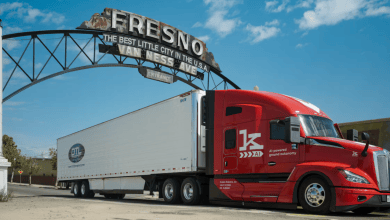 Red tractor-trailer equipped with the Kodiak Driver parked beneath the Fresno arch sign in Fresno, California