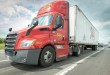 a red Saia daycab pulling a 53-foot Saia trailer on a highway