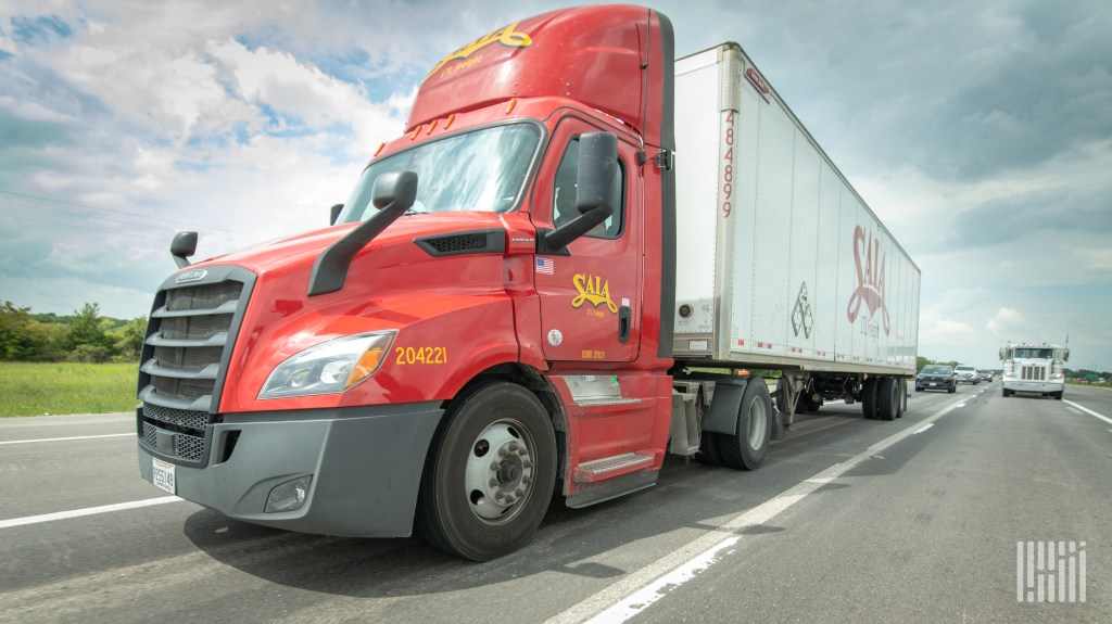 a red Saia daycab pulling a 53-foot Saia trailer on a highway