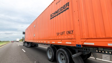 An orange Schneider intermodal container being hauled by a truck
