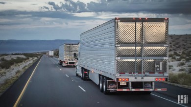 Two trucks driving on a two lane highway at dusk